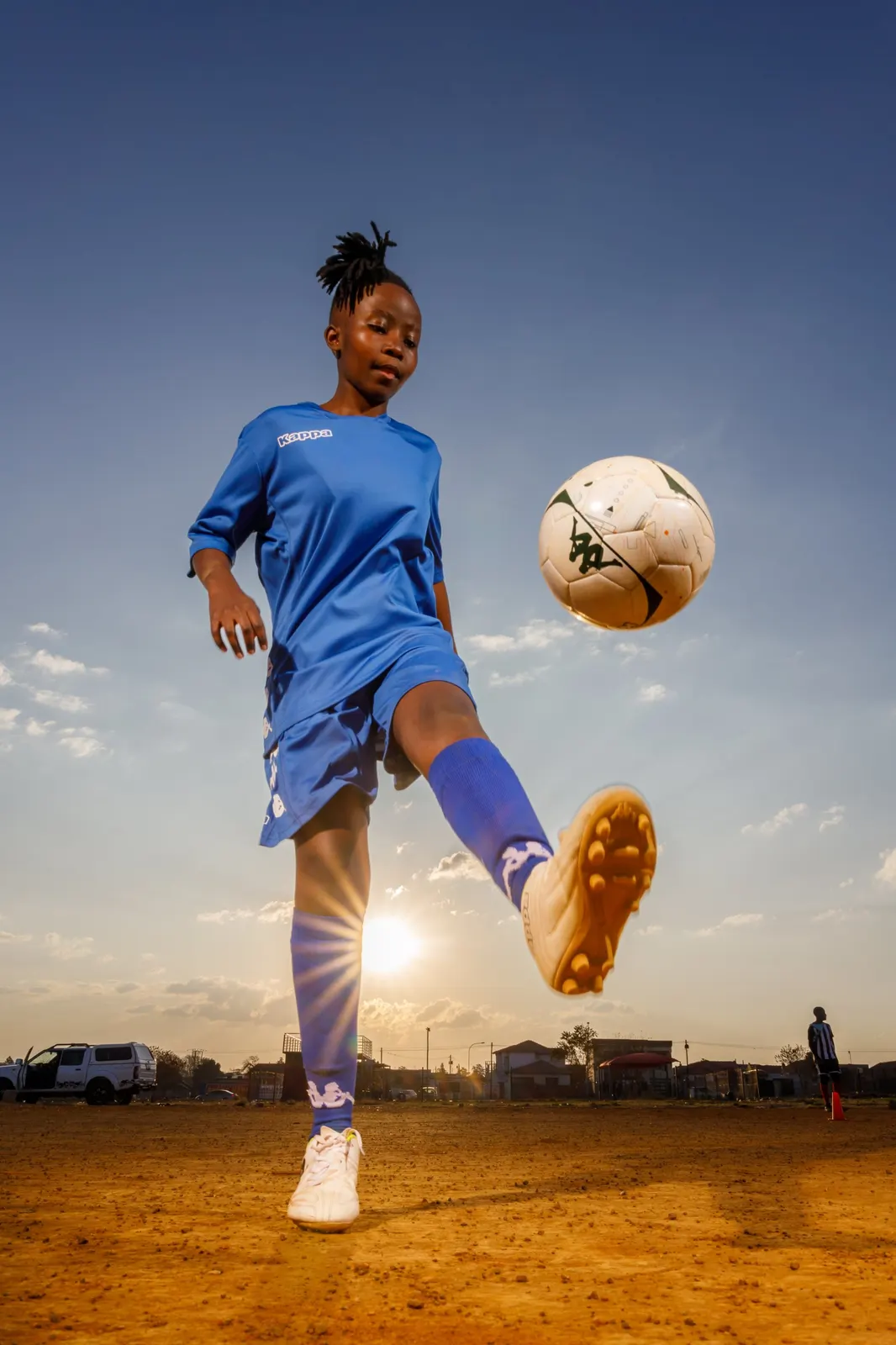 Girl footballer kicking a ball at sunset, Kappa campaign photography